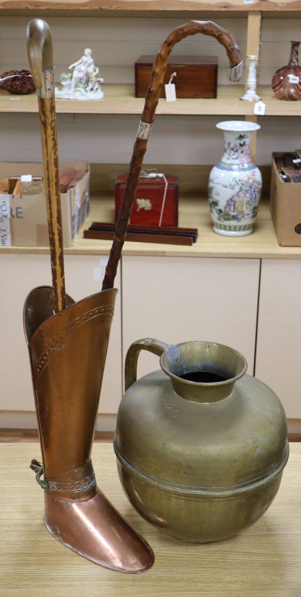 A copper stickstand shaped as a riding boot, height 52cm, two silver mounted walking sticks and a large brass jug, height 35cm